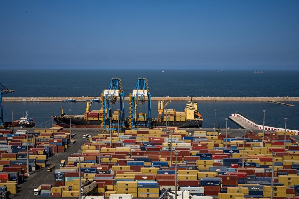 Expansive view of Oráns bustling port, showcasing colorful cargo containers and cranes by the sea.